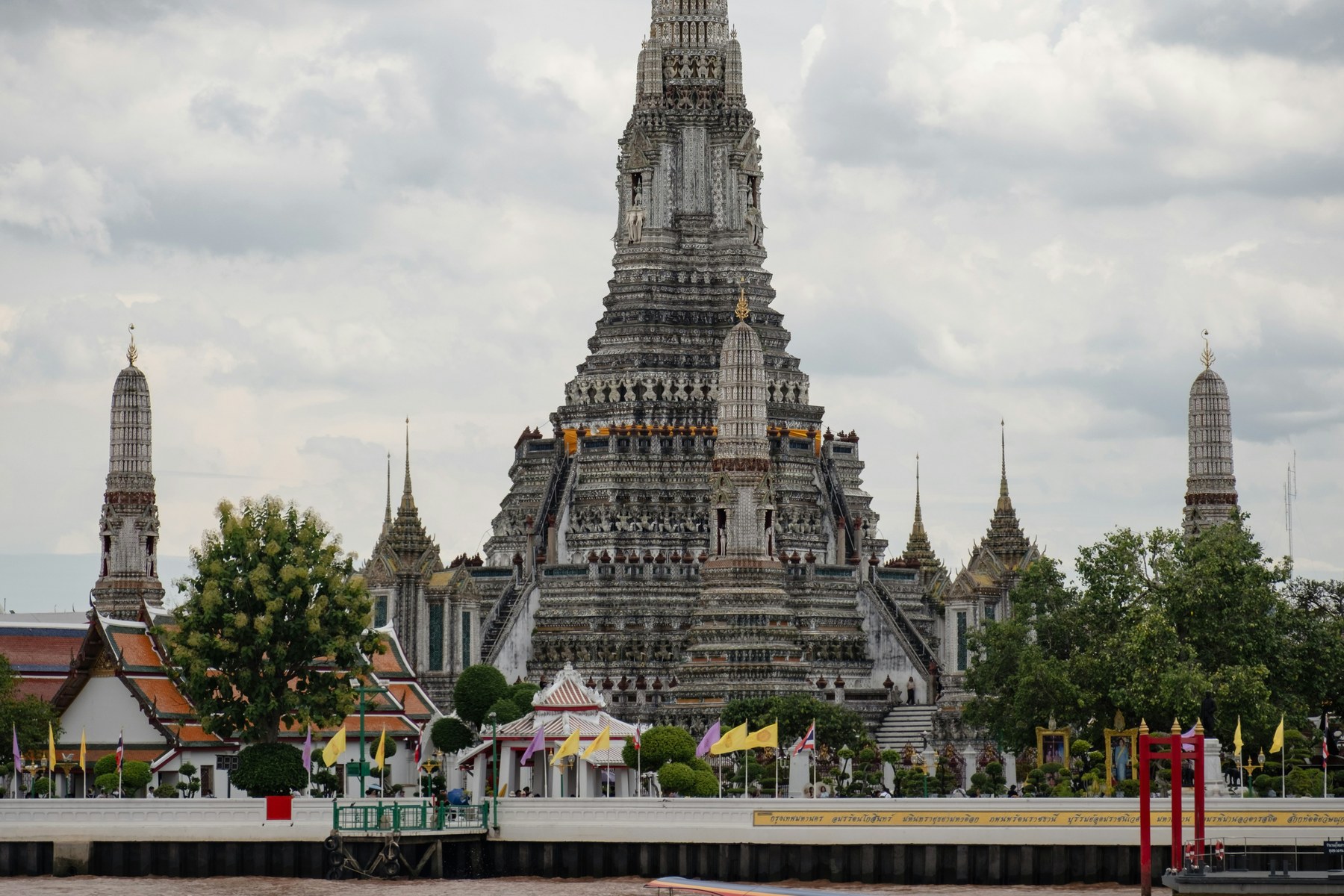 Wat Arun beside the Chao Phraya River in Bangkok, with a long-tail boat in the foreground.