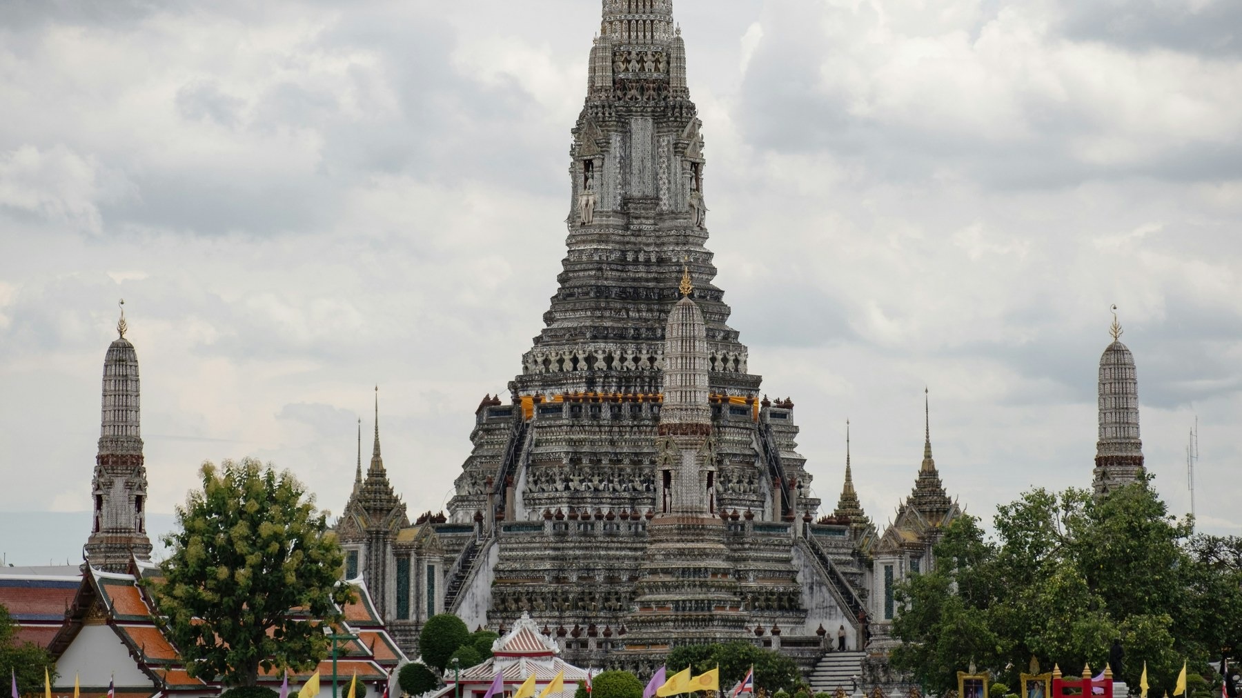 Wat Arun beside the Chao Phraya River in Bangkok under a warm sky.